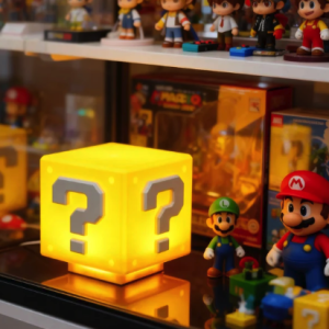 Glowing Super Mario Question Block lamp surrounded by various video game figurines and collectibles on a display shelf.