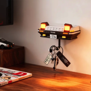 Desk featuring a white Toyota AE86 Trueno key holder with illuminated headlights, a model car, and Initial D manga.