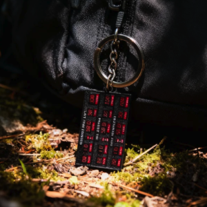 Back to the Future time machine DeLorean keychain on mossy forest ground with a black backpack.