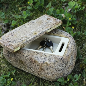 Realistic fake rock key hider open with keys inside on green grass.