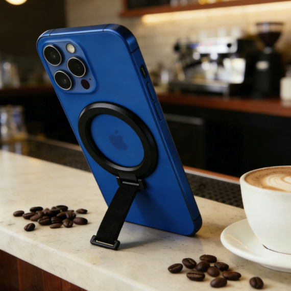 Blue iPhone with MagSafe kickstand, coffee, and beans on a cafe counter.