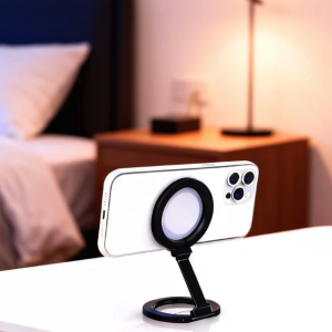 White smartphone securely held horizontally on a black magnetic adjustable phone stand on a white table.