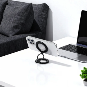 White smartphone horizontally resting on a black magnetic foldable ring phone stand on a white desk.