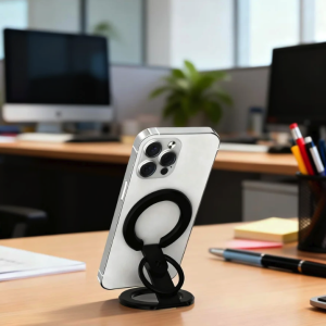 Silver smartphone with black ring stand on a wooden office desk.